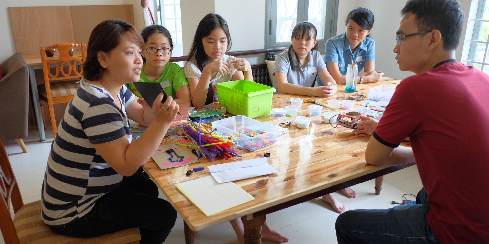 Cô giáo đang hướng dẫn sơ về cách làm thiệp cho các bạn