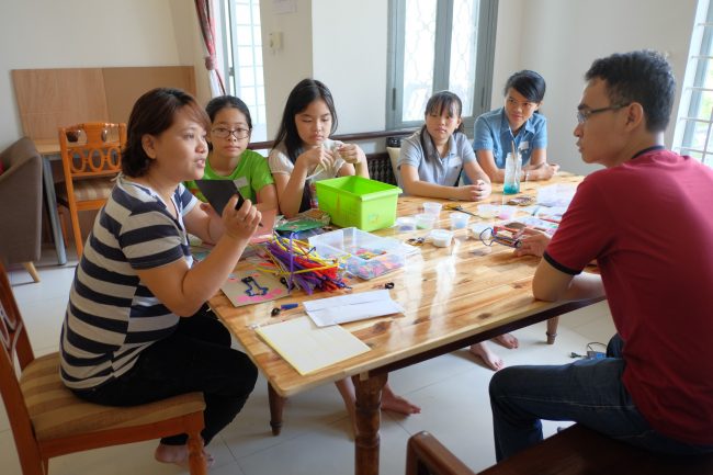 Cô giáo đang hướng dẫn sơ về cách làm thiệp cho các bạn
